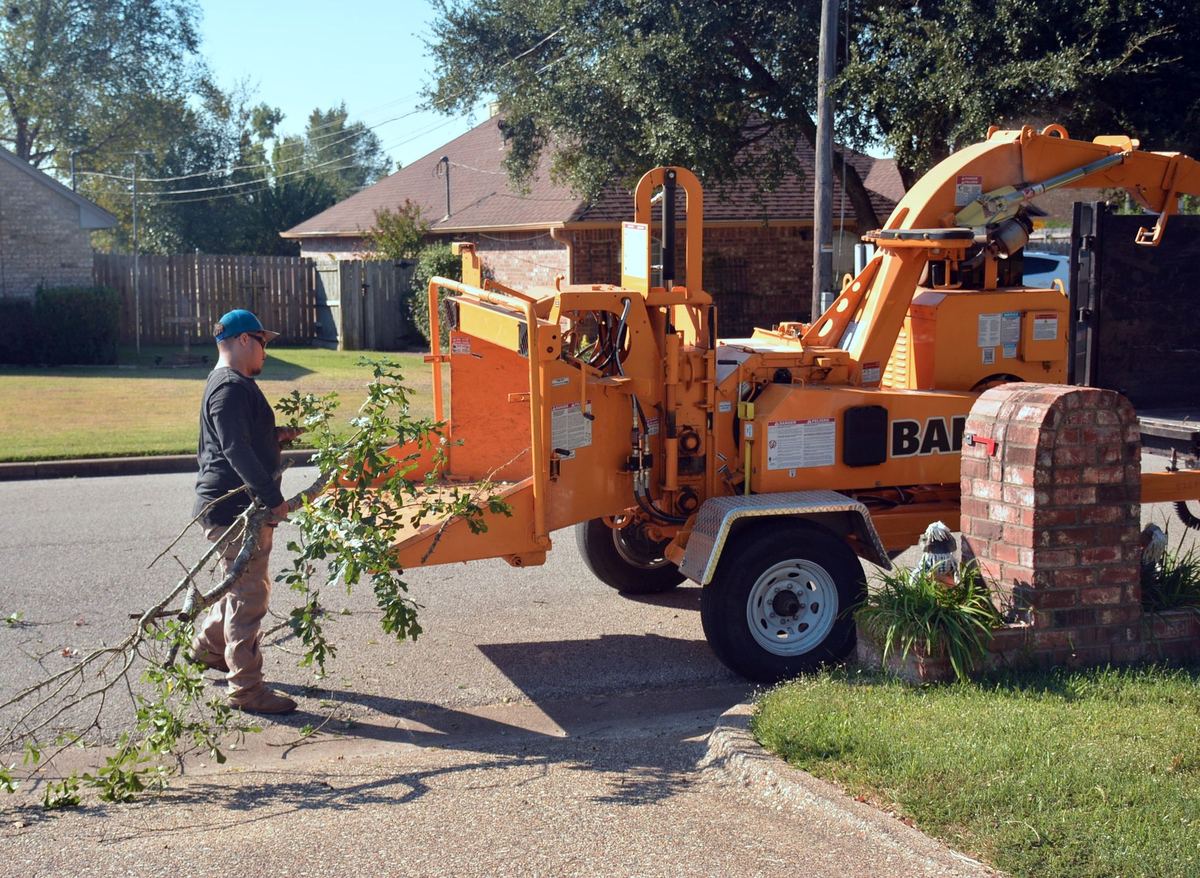 Crew feeding branches into a wood chipper on a residential street
